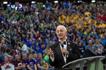 Dr. Woodie Flowers speaking at a podium at the FIRST Championship